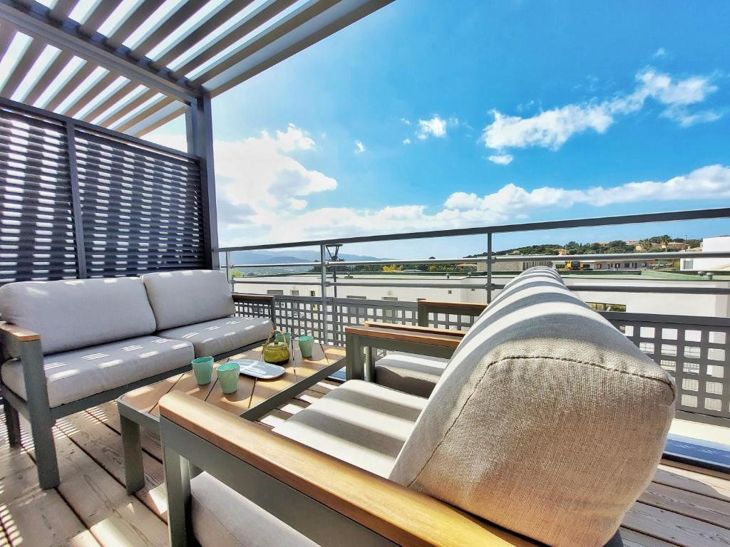 d'une terrasse avec un canapé et une table sur un balcon. dans l'établissement Appartement CATALINA - Double terrasse - WIFI - Clim - PORTICCIO, à Porticcio