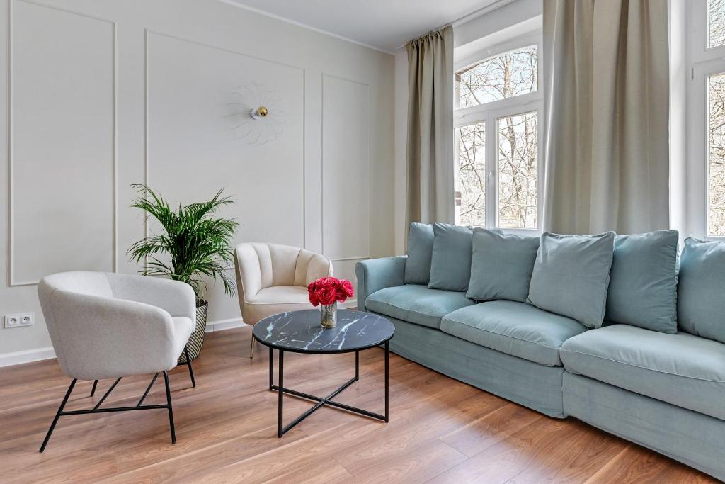 a living room with a blue couch and two chairs and a table at Lion Apartments - Capri in Sopot