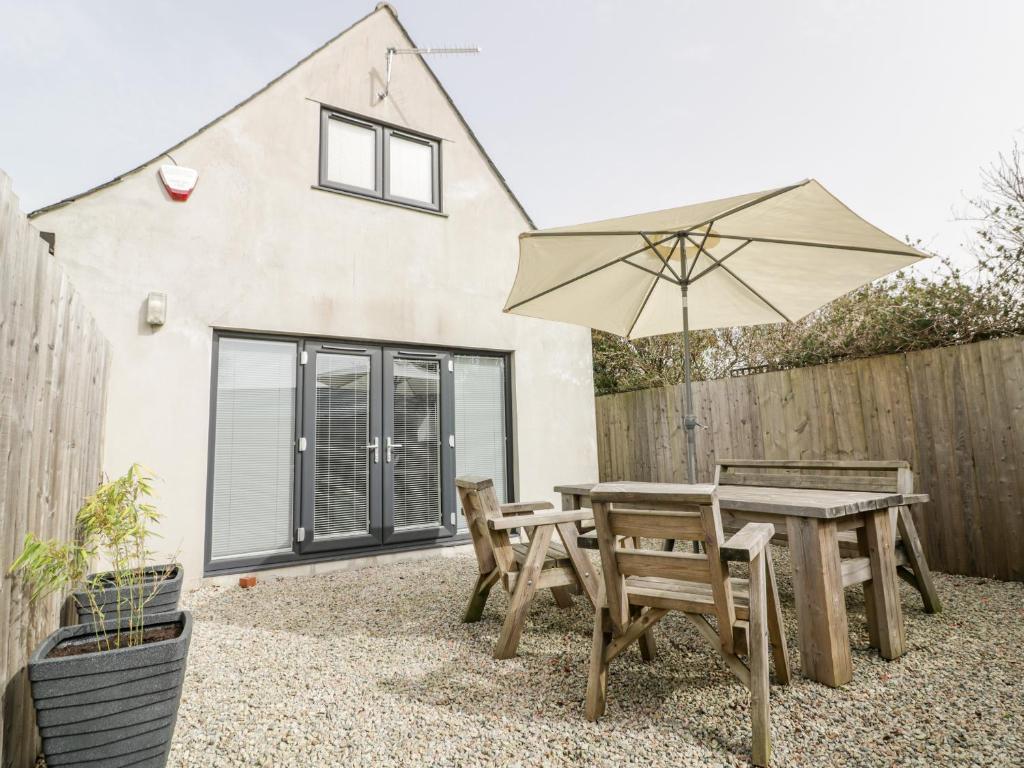 a picnic table and an umbrella in front of a house at Lily Cottage in Camelford