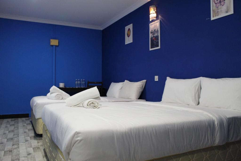 2 camas en una habitación con paredes azules en Sky View Hotel Dengkil PUTRAJAYA, en Kampung Dengkil