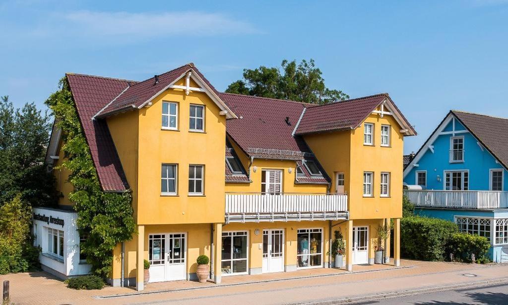 a yellow house with brown roofs on a street at Kiek Över in Ahrenshoop