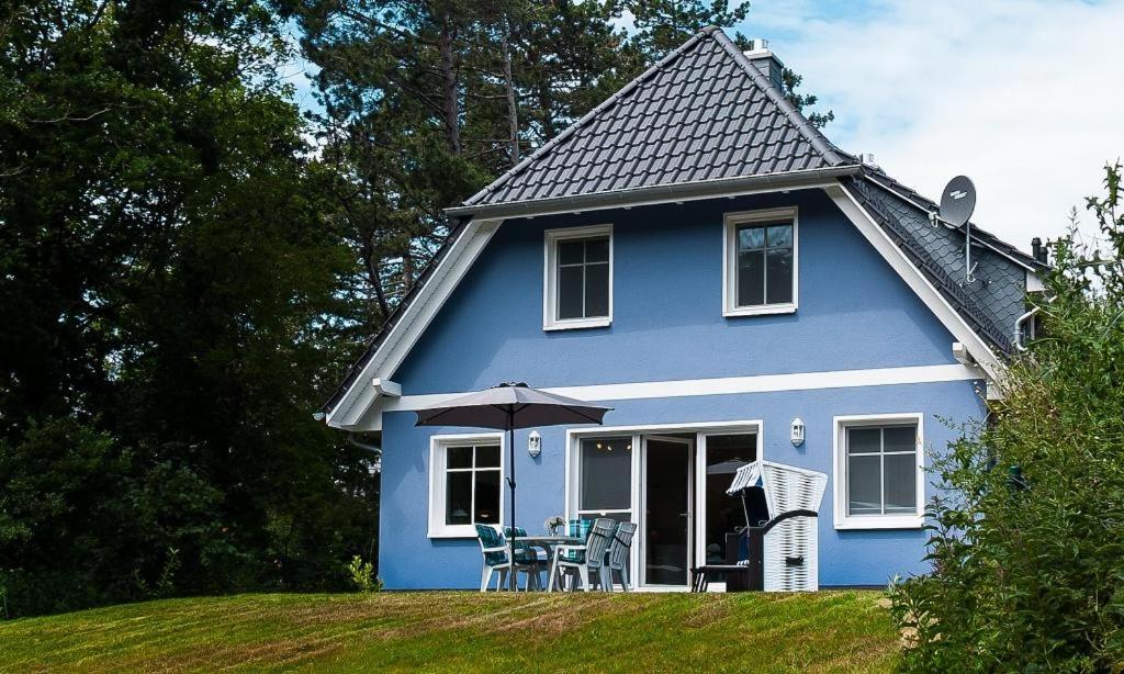 uma casa azul com cadeiras e um guarda-sol em Strandhaus Gabriella 02 em Ahrenshoop