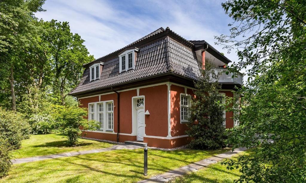 a red house with a white door in a yard at Villa Sonnenfrieden 01 in Ahrenshoop