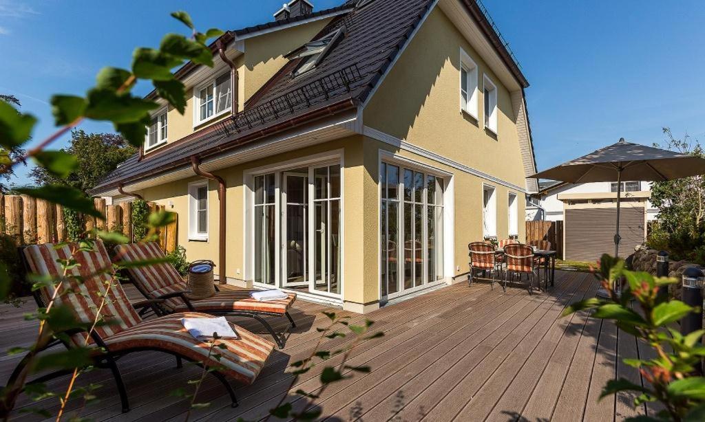 a house with two benches and an umbrella on a deck at Haus Seeschwalbe in Ahrenshoop