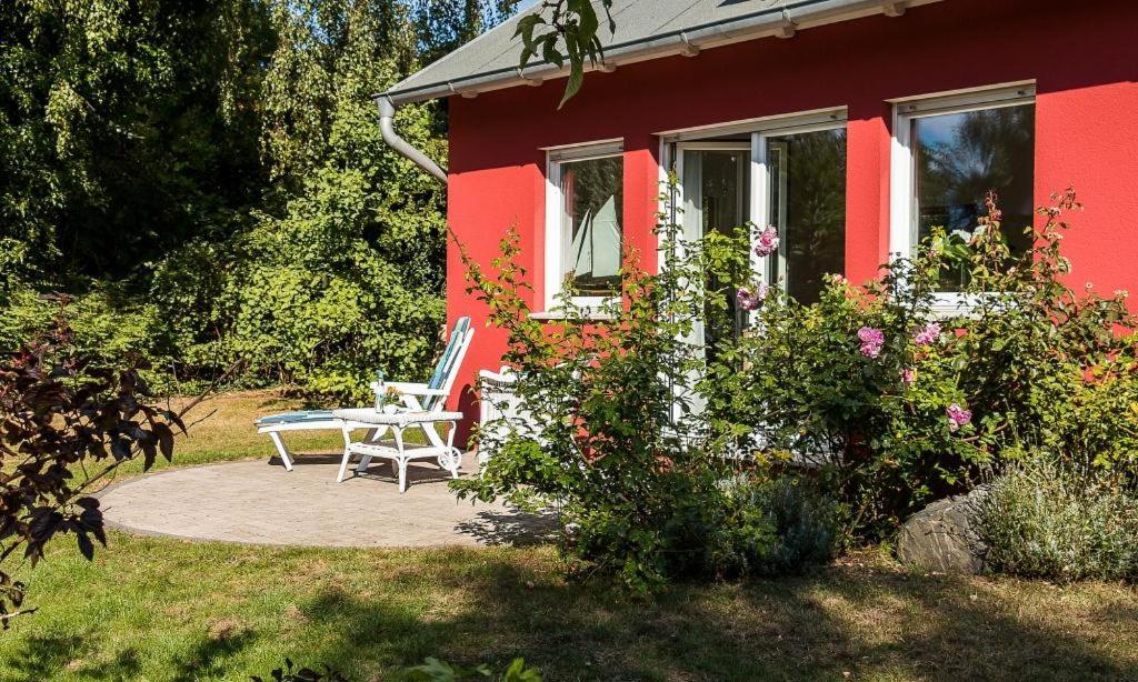 a red house with a table and a chair outside at Meertraum in Ahrenshoop