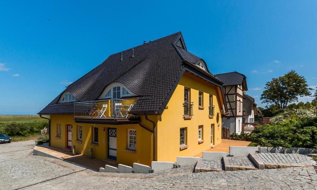 ein gelbes Haus mit schwarzem Dach in der Unterkunft Pommernhus Ostseeblick in Ahrenshoop