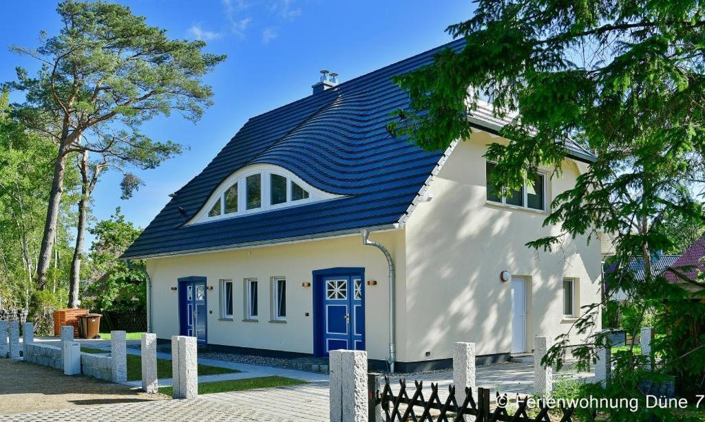 a white house with a blue door and a fence at Düne 7 in Dierhagen