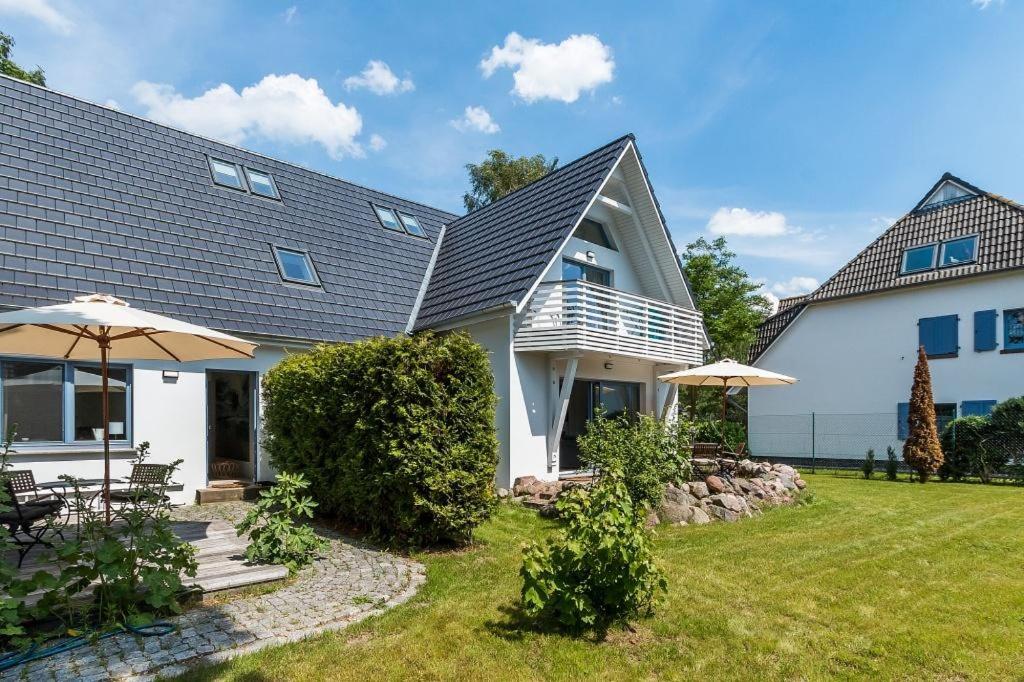 a white house with an umbrella and a yard at Drei Akazien Wohnung 2 in Neuhaus