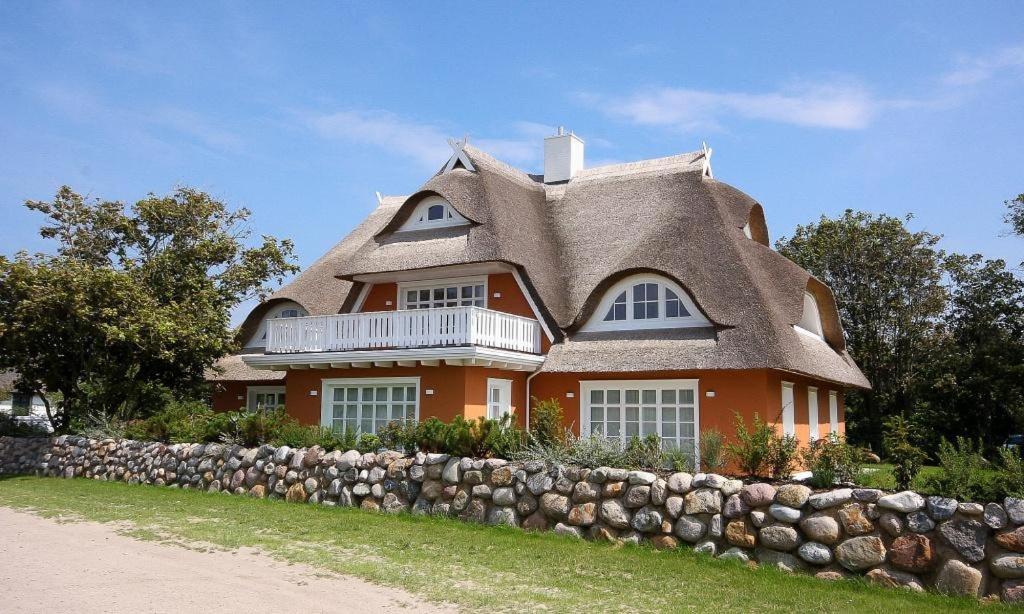 ein großes orangefarbenes Haus mit einem Strohdach in der Unterkunft Strandhaus hinter der Düne in Ahrenshoop