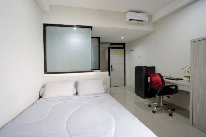 1 dormitorio con 1 cama blanca y 1 silla roja en DPARAGON KALIJUDAN, en Surabaya