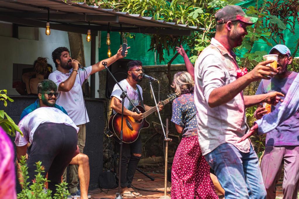 un grupo de personas cantando y tocando instrumentos en un escenario en The Lost Hostel, Varkala - Helipad, en Varkala