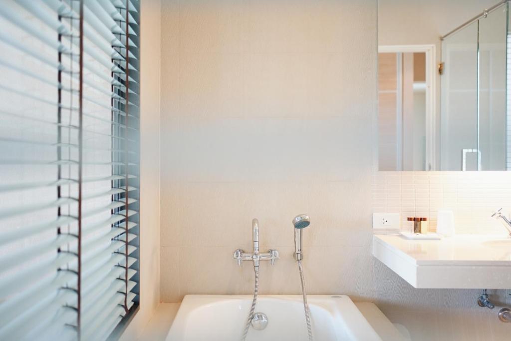 a bathroom with a bath tub and a sink at Palm Crescent Hua Hin in Cha Am