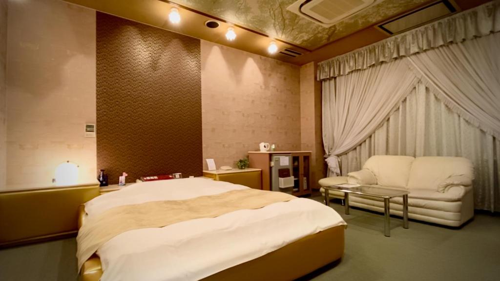 a bedroom with a large bed and a chair at Hotel Sagano (Adult only) in Kyoto