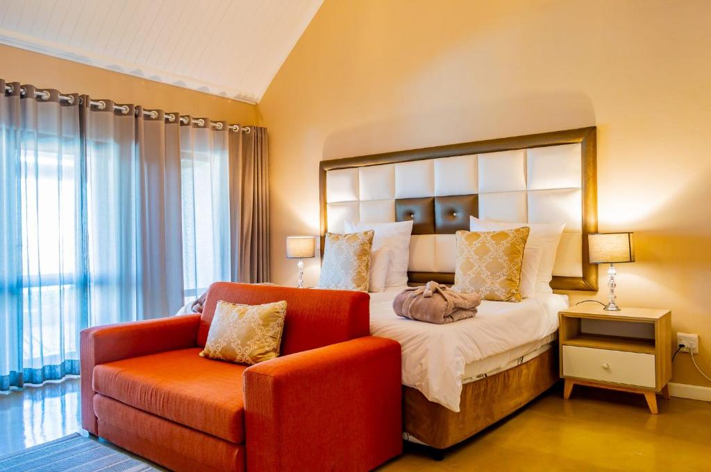 een slaapkamer met een groot bed en een rode stoel bij Mount Shekinah Country Hotel in Balgowan