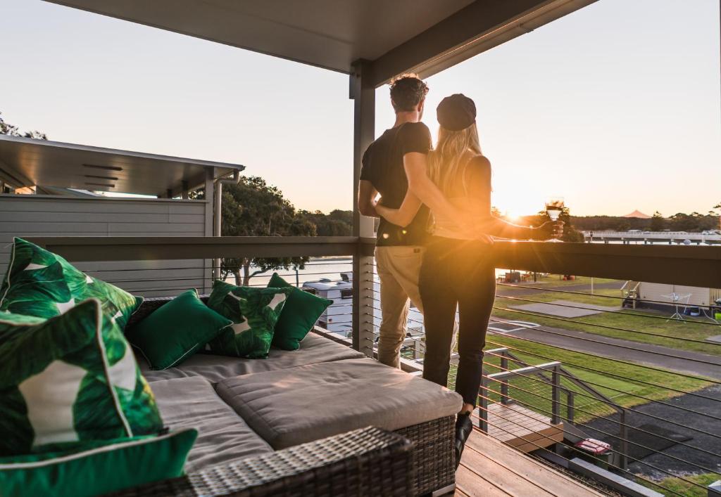 un hombre y una mujer de pie en un balcón con vistas por la ventana en Holiday Haven Burrill Lake, en Burrill Lake