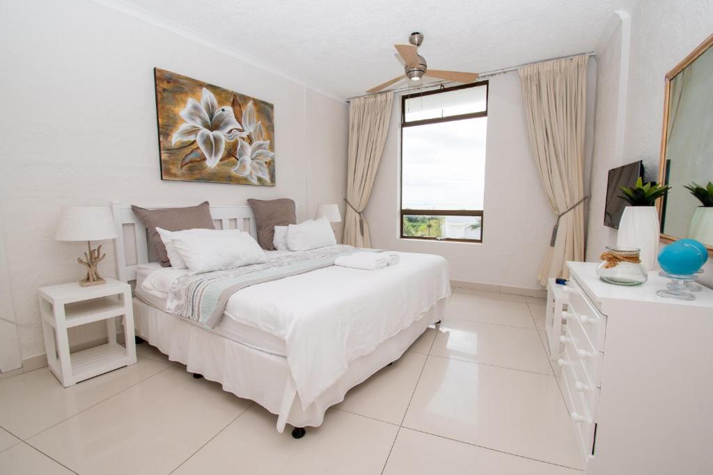 ein weißes Schlafzimmer mit einem Bett und einem Fenster in der Unterkunft 516 Breakers Resort Umhlanga Rocks in Durban