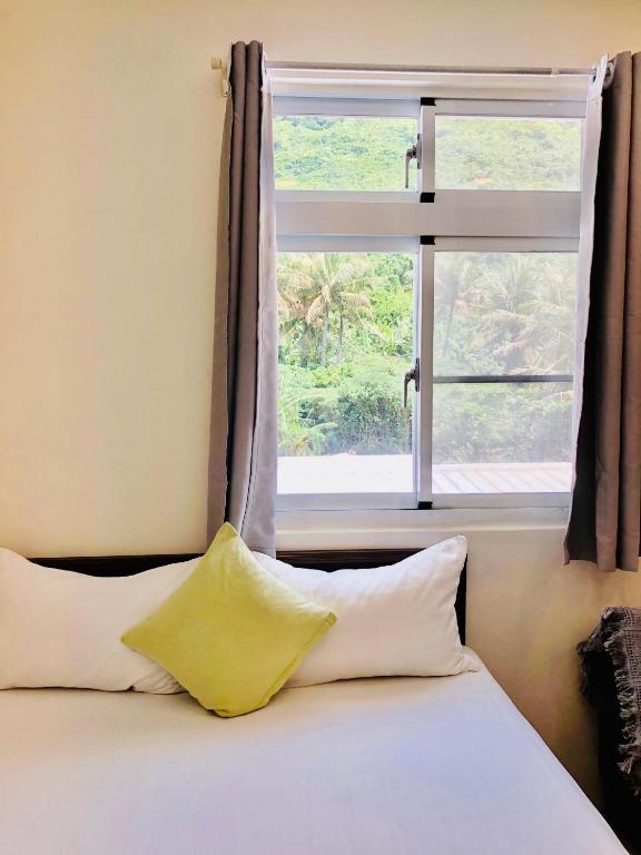 a bed with two pillows and a window at Shang Yuan in Green Island
