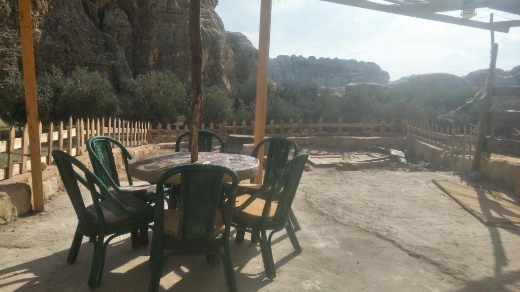 a table and chairs on a patio with a view at Petra Cottage in Al Ḩayy