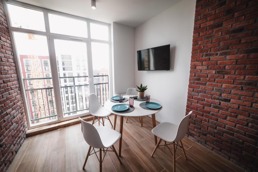 een eetkamer met een bakstenen muur en een tafel en stoelen bij Kostjukowski Apartments Shevchenka 60 in Lviv