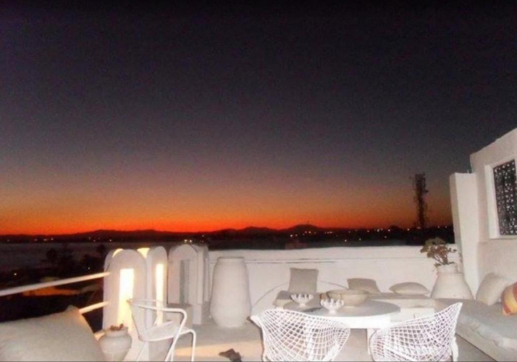 un soggiorno con tavolo, sedie e tramonto di le mirador a Hammamet