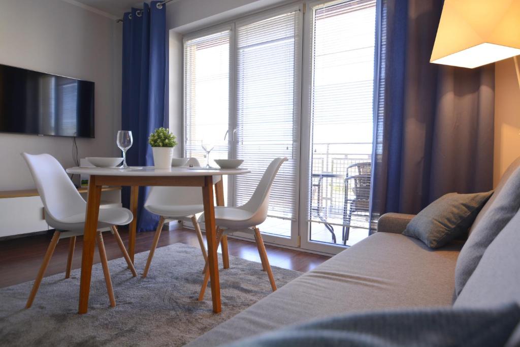 ein Wohnzimmer mit einem Tisch, Stühlen und einem Sofa in der Unterkunft Apartamenty Bryza in Świnoujście