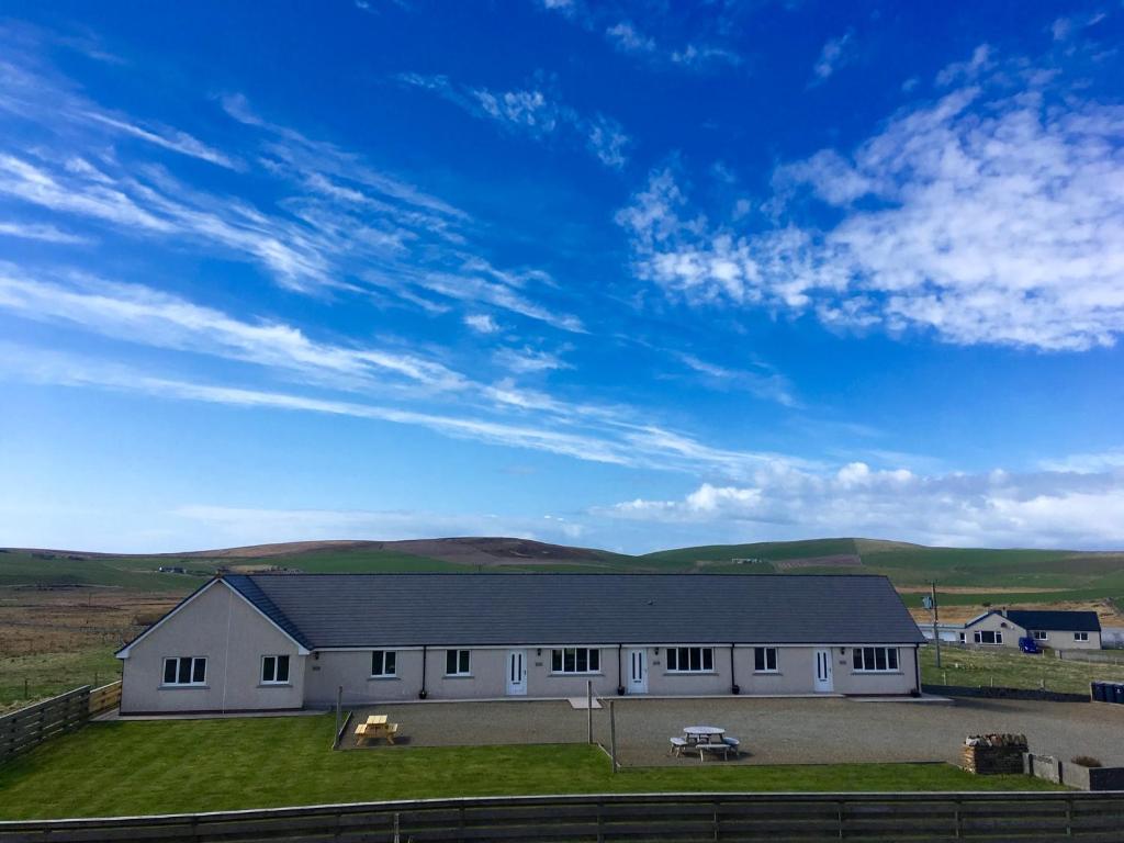 a large white barn with a blue sky at Eastbrae Cottages & Lodges in Stromness
