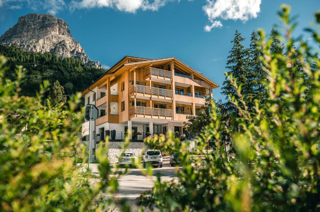 ein großes Gebäude mit einem Berg im Hintergrund in der Unterkunft Garni Larix in Kolfuschg