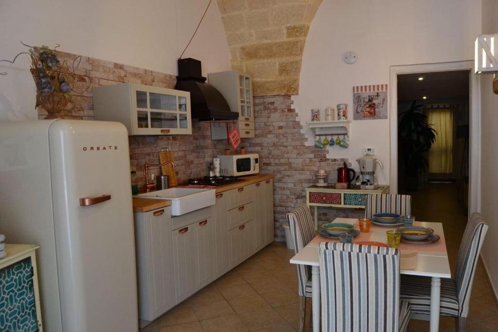 Il comprend une cuisine équipée d'une table et d'un réfrigérateur blanc. dans l'établissement Casa Melania, à Brindisi