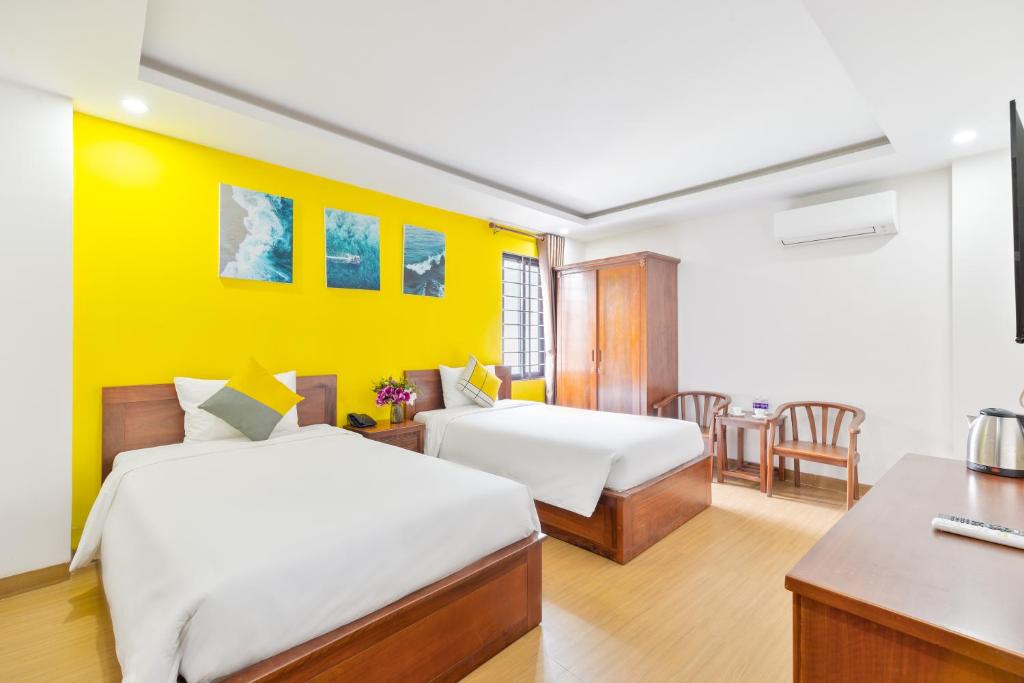 a hotel room with two beds and a desk and a table at The Samson - Beach Boutique Hotel in Da Nang