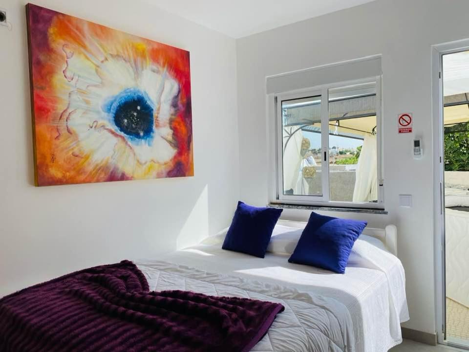 um quarto com uma cama com um quadro na parede em Kerart House em Armação de Pêra