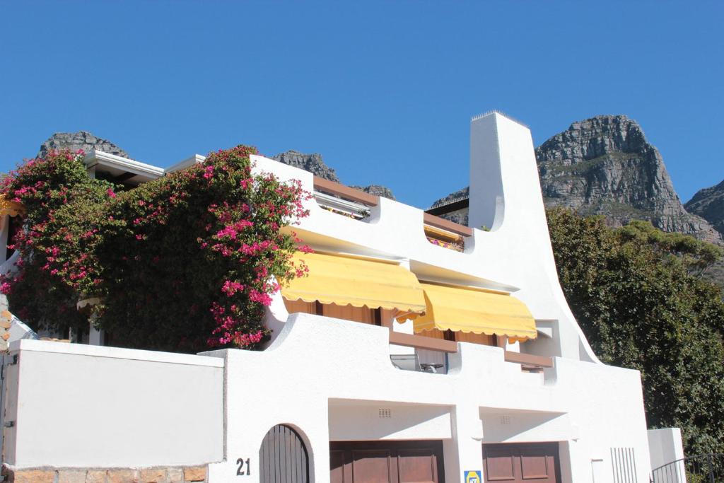 een wit gebouw met bloemen aan de zijkant bij Sunset Apartment in Kaapstad