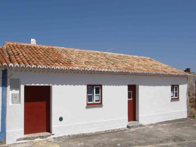 un edificio blanco con puerta roja y techo en Casa da Tia Maria By Alojamentos Vitinho, en São Luis