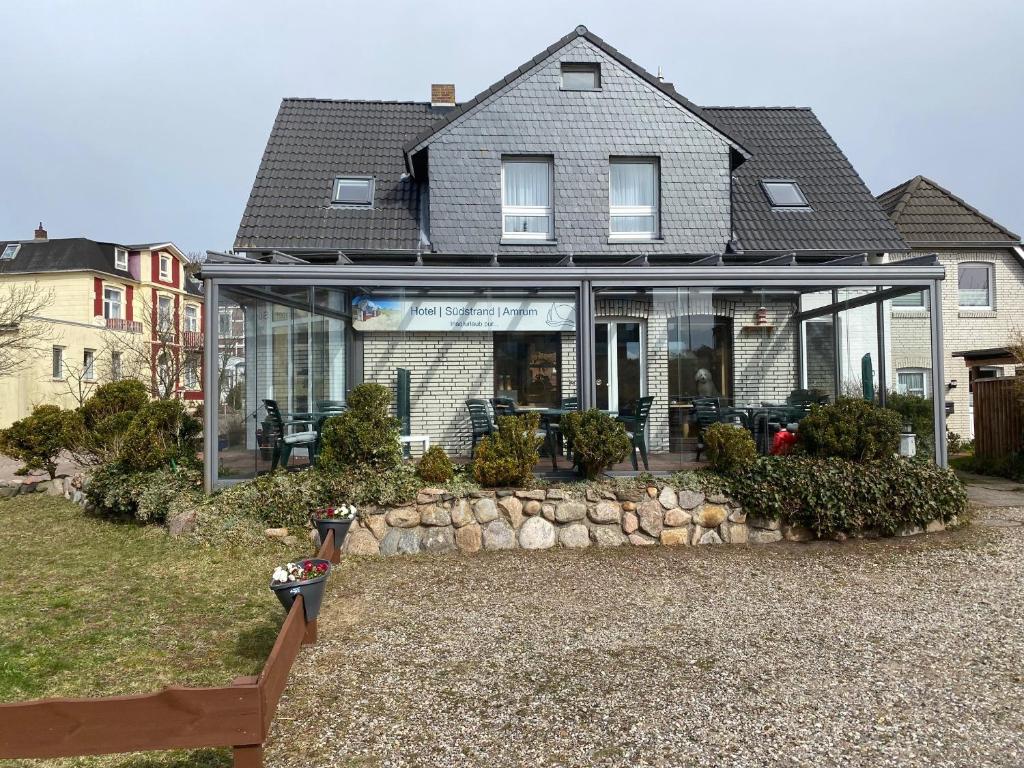 ein Haus mit Glastüren an der Vorderseite in der Unterkunft Hotel Südstrand Amrum in Wittdün