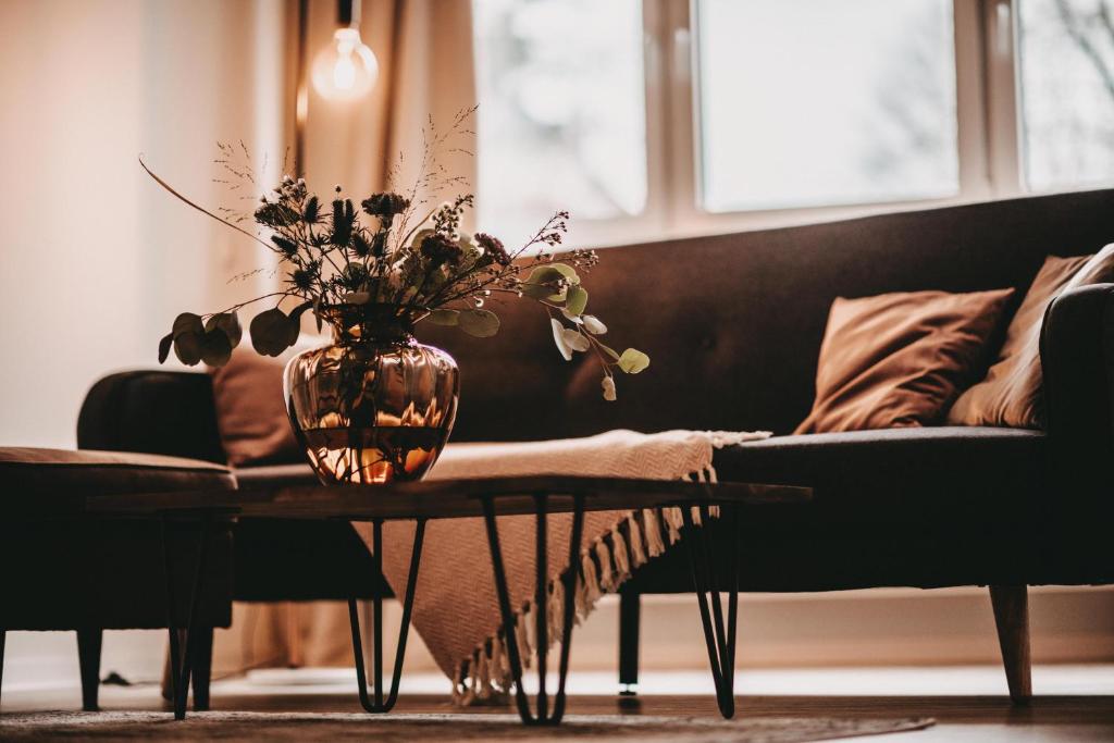 ein Wohnzimmer mit einer Vase auf einem Tisch und einem Sofa in der Unterkunft THE LOFT LODGE - ATELIER in Braunschweig