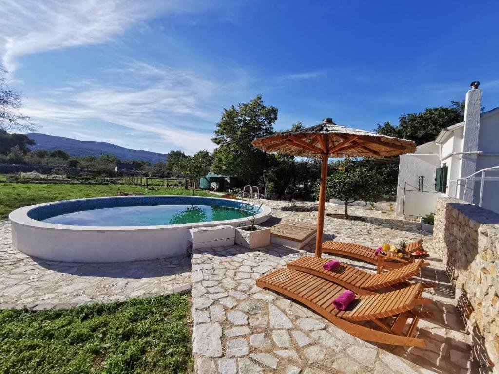 斯塔里格勒Hvar Mediterranean Ranch House的一个带两把椅子和遮阳伞的游泳池