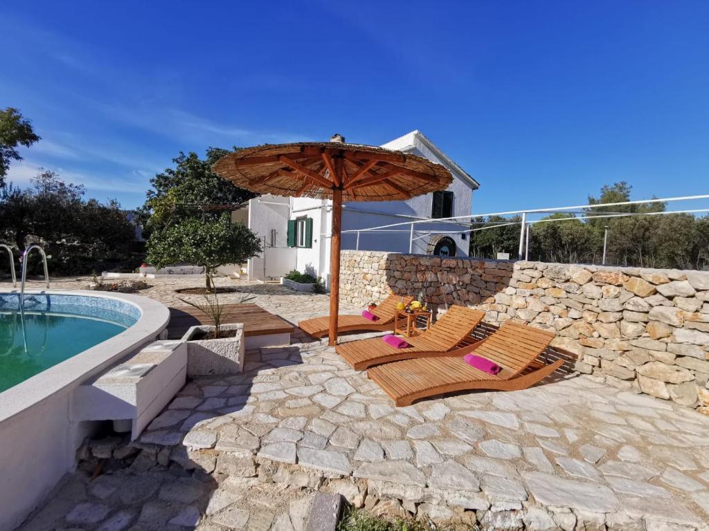 斯塔里格勒Hvar Mediterranean Ranch House的一个带两把椅子和一把遮阳伞的庭院,毗邻一个游泳池