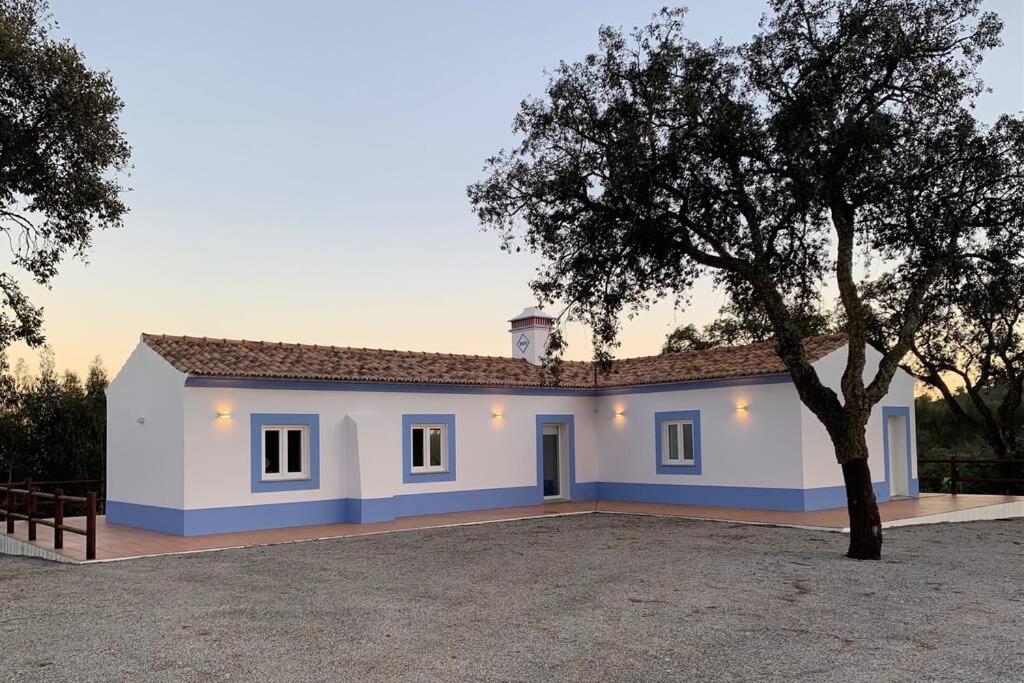 a white house with a tree in front of it at Monte da Rocha in Santiago do Cacém