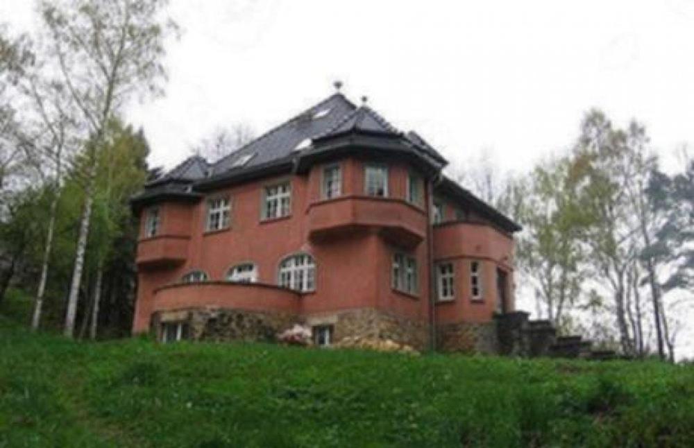 duży budynek z czerwonej cegły na trawiastym wzgórzu w obiekcie Baltic Home w Polanicy Zdroju