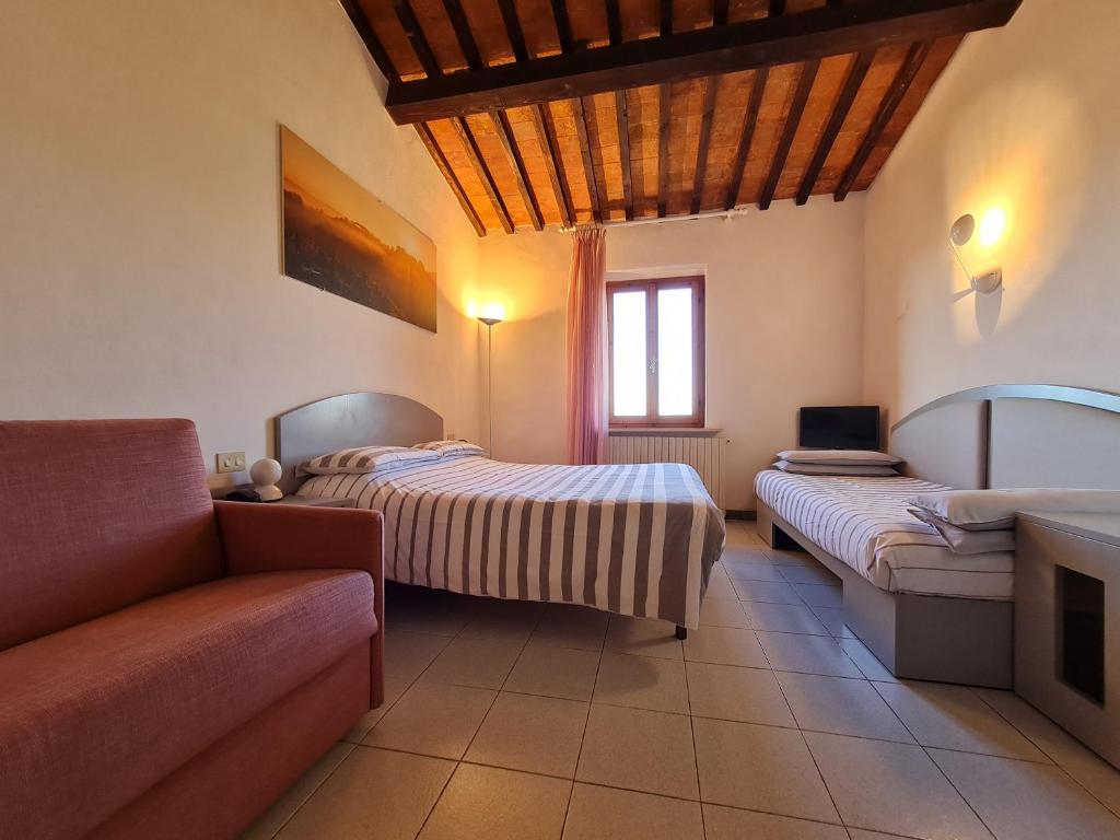 Cette chambre comprend deux lits, un canapé et une télévision. dans l'établissement Hotel Da Graziano, à San Gimignano