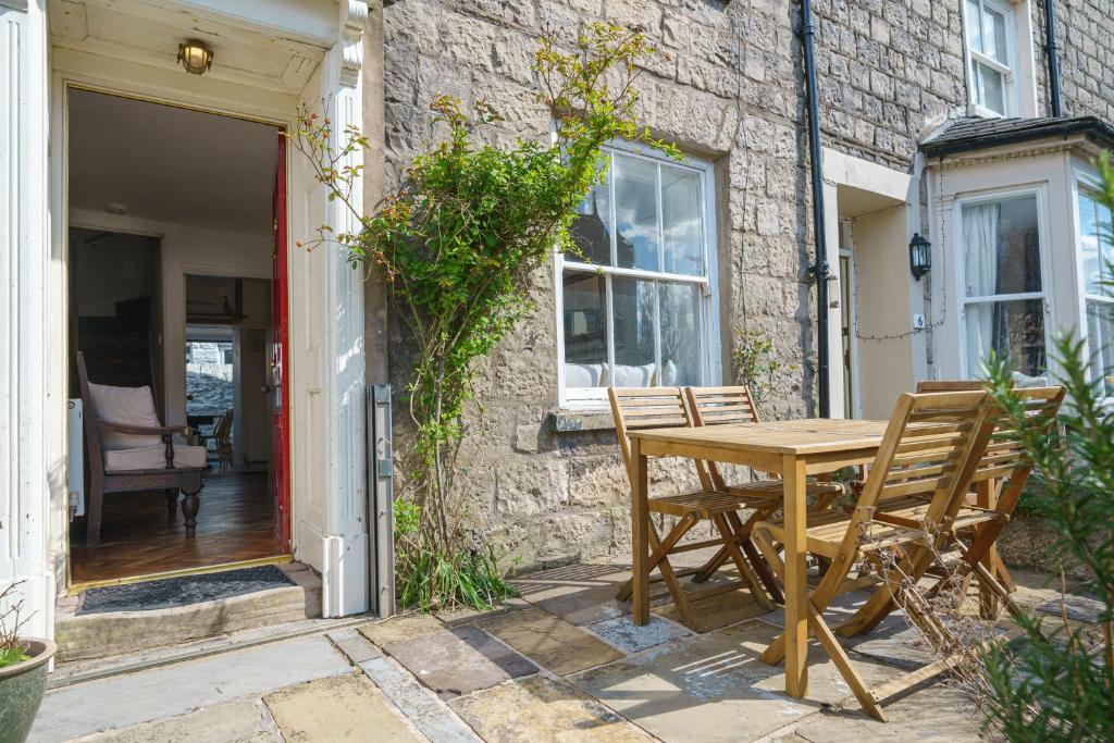a wooden table and chairs in front of a house at Church View Cottage in Kendal