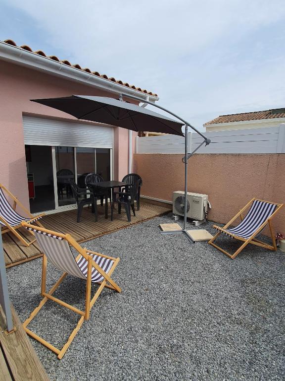un patio avec une table, des chaises et un parasol dans l'établissement DUPLEX BASSIN D'ARCACHON, à Gujan-Mestras