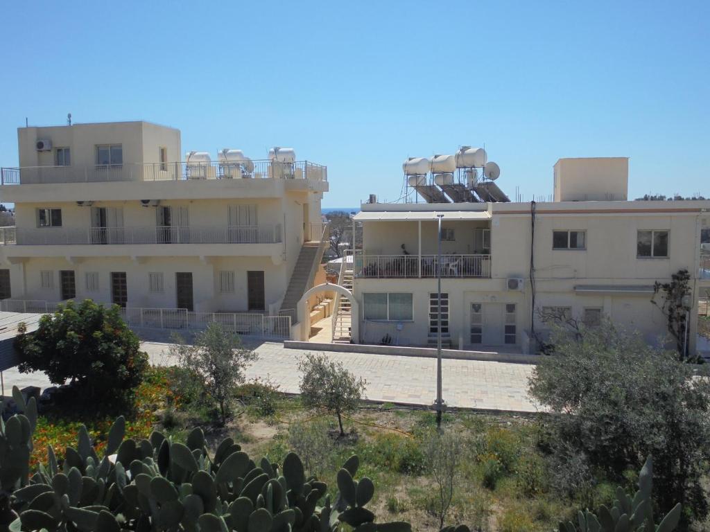 a view of two buildings with plants in the foreground at Niki Court Holiday Apartments in Paphos City