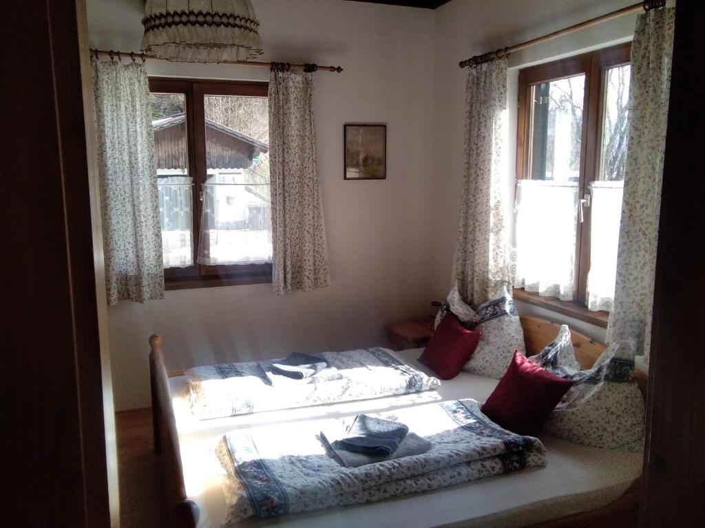 a bedroom with a bed and two windows at Appartements direkt am See in Grundlsee