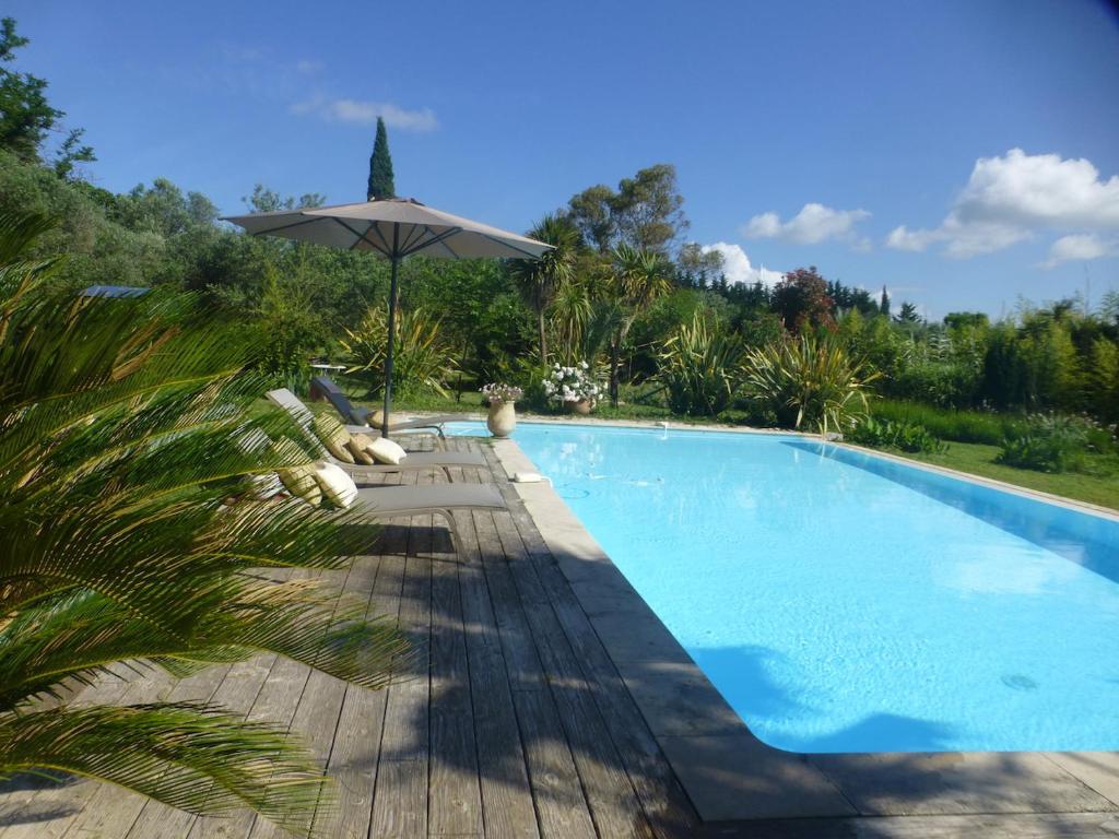 a swimming pool with an umbrella and chairs next to it at Domaine Sesquier Mas d'exception Jasmin in Mèze