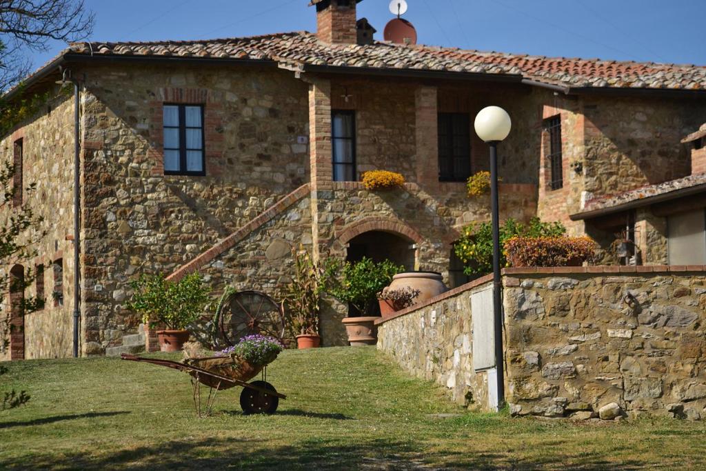 una casa de piedra con una carretilla delante de ella en Casalgallo en Quercegrossa