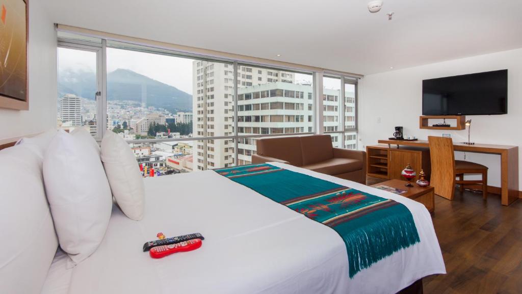 a bedroom with a white bed and a large window at ZEN Hotel in Quito