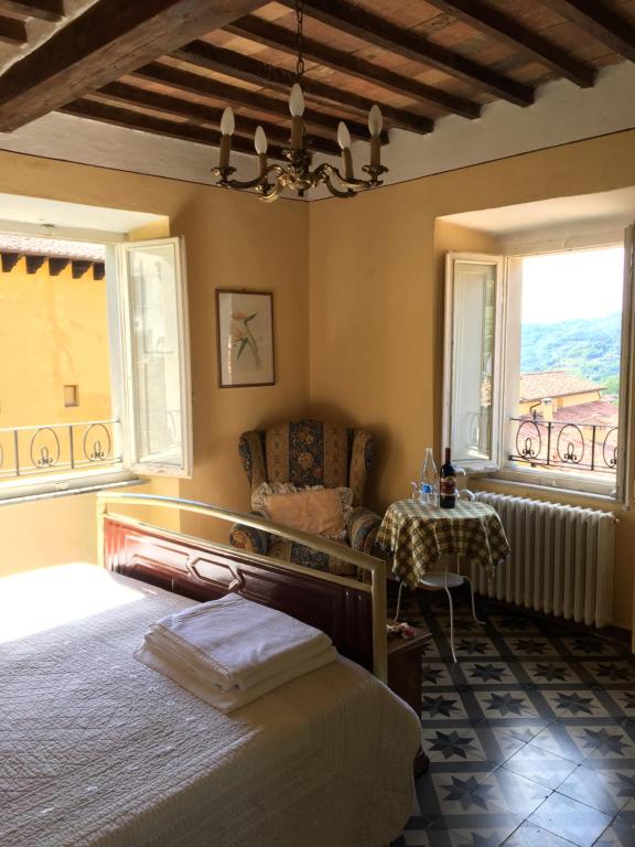 a bedroom with a bed and a chair and two windows at Barga Lucca Centro Storico Con giardino in Barga
