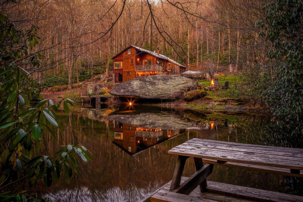 a house in the middle of a lake with a bench at Serene mountain getaway, Hot Tub, Sauna, Lake View, Swim, Fish, Hiking, EV plugin in Boone