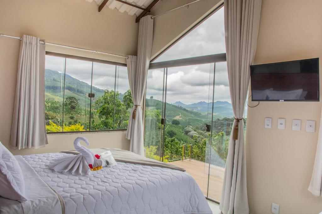 ein Schlafzimmer mit einem Bett und einem großen Fenster in der Unterkunft Mirante das Montanhas in Divisa