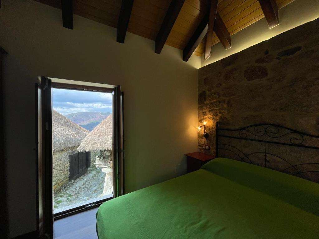 um quarto com uma cama verde e uma janela em Casa Casoa em Piornedo